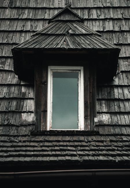 Attic roof framing shows condensation droplets, damp insulation, and dark moisture stains on the wood deck.